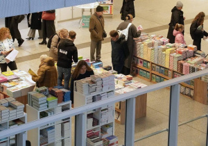 Zdjęcie z góry przedstawia fragment hali dworca Łódź Fabryczna. Widać stragany z książkami oraz ludzi odwiedzających targi.