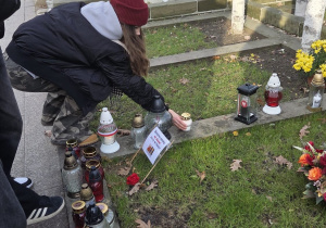Uczniowie zapalają znicze na grobach bohaterów książki Kamienie na szaniec na Cmentarzu Powązkowskim.