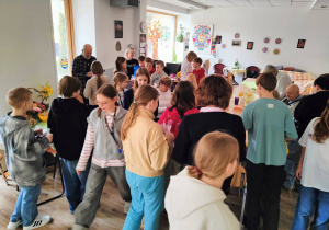 W pomieszczeniu stoją nasi uczniowie wraz z Seniorami.