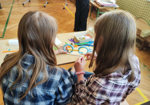 Dwie dziewczynki siedzą przy stole i budują model roweru.