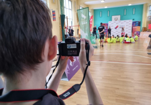 Uczeń na sali gimnastycznej robi zdjęcie kolegom uczestniczącym w zajęciach Pho3nix Active School