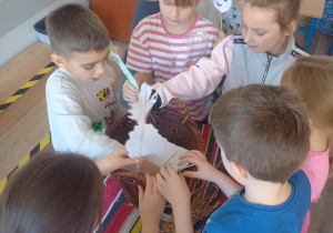Dzieci zgromadzone wokół koszyka przygotowują inscenizację wiersza.