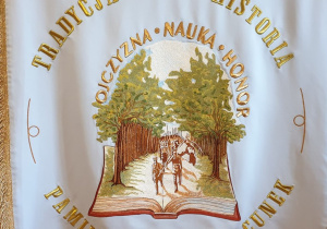 Druga strona przedstawia książkę, z której wyrasta las, a z lasu wychodzą żołnierze ze sztandarem. Nad obrazkiem jest napis: Ojczyzna, Nauka, Honor. Na obrzeżu tej strony sztandaru widnieje napis: Tradycja, Historia, Szacunek, Pamięć.
