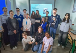 Na zdjęciu uczniowie biorący udział w konkursie. Stoją na tle tablicy multimedialnej.