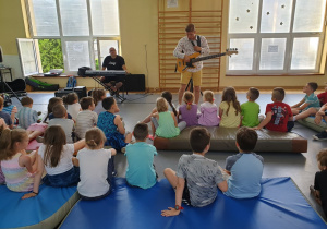 uczniowie słuchają dźwięków gitary basowej