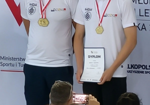 Na najwyższym stopniu podium stoi Mateusz Sekściński wraz z trenerem.