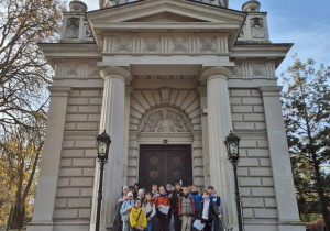 Na schodach na tle budynku stoi grupa uczniów