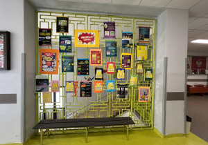 Na szkolnym korytarzu na kracie wiszą plakaty promujące noszenie odblasków.