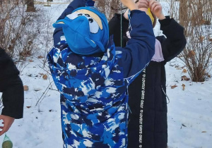 W parku dwoje dzieci wiesza pokarm dla ptaków