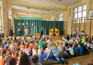 W sali gimnastycznej na materacach siedzą dzieci. Oglądają przedstawienie.