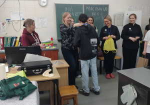 W pomieszczeniu stoi kilka kobiet. Jedna z nich wręcza medal naszemu uczniowi.