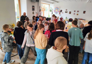 W pomieszczeniu stoją nasi uczniowie wraz z Seniorami.