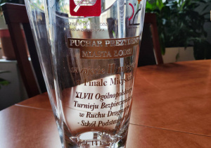 Na stole stoi szklany puchar - nagroda dla uczestników konkursu.