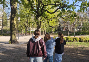Trzy uczennice stoją w parku pod drzewem
