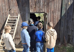 Uczniowie wchodzą do drewnianego domu