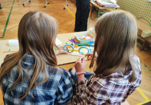 Dwie dziewczynki siedzą przy stole i budują model roweru.