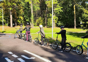 W parku na uliczkach motodromu widać dzieci na rowerach.
