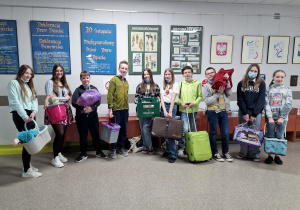 grupa uczniów klasy 7c prezentuje wiadra, walizki i torby jako zamienniki plecaków