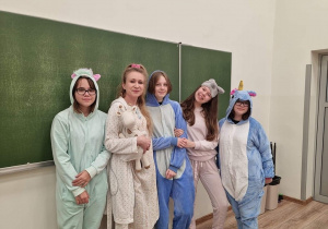 cztery uczennice wraz z nauczycielką stoją w klasie przed tablicą, są ubrane w piżamy