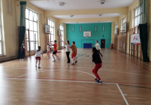 grupa dzieci uczestniczy w zajęciach sportowych na sali gimnastycznej