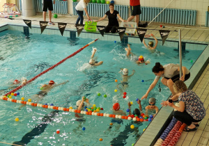 na basenie duża grupa dzieci uczestniczy w konkurencji zbierania piłek z wody