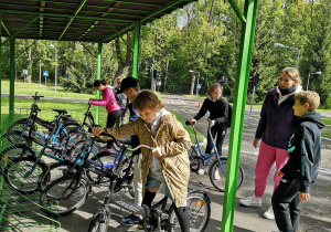 grupa dzieci stoi przy rowerach, wybierają rowery