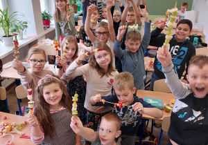 na zdjęciu widać grupę dzieci, które trzymają w rękach przygotowane przez siebie warzywno-owocowe szaszłyki
