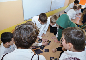 grupka chłopców siedzi w klasie, układają puzzle
