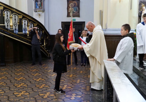 dziewczynka przekazuje księdzu w darze chleb
