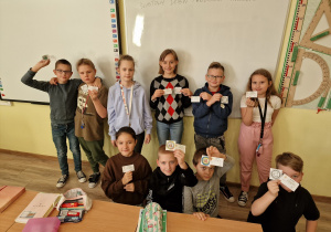 na zdjęciu grupa uczniów klasy 4b stoi w klasie, prezentuje odznaki eksperta