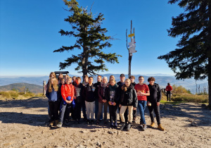 grupa uczniów klasy 8c wraz z wychowawcą stoi na górze pod tabliczką z napisem "Barania Góra"