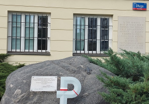 Przed budynkiem stoi duży głaz, na którym jest znak Polski Walczącej oraz tablica upamiętniająca 60 rocznicę akcji pod Arsenałem