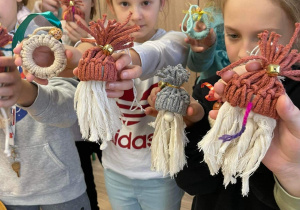 Dzieci trzymają w rękach swoje prace czyli makramowe ozdoby świąteczne.