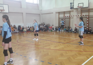Na sali gimnastycznej stoją ustawione do gry dziewczynki ze szkolnego zespołu.