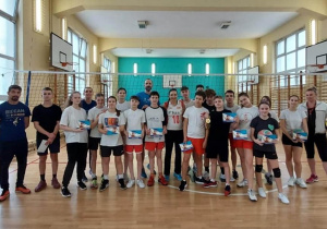Na sali gimnastycznej w strojach sportowych stoją uczniowie, nauczyciele oraz pani Małgorzata Niemczyk. Zdjęcie grupowe.
