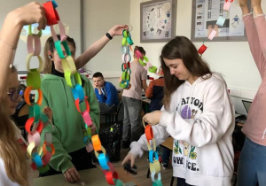 Uczniowie w klasie robią kolorowy łańcuch. Pokazują również ile już zrobili.