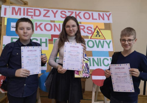Troje naszych uczniów stoi przed tablicą z nazwą konkursu. Trzymają w rękach dyplomy.
