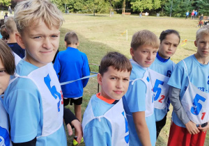 Na zdjęciu chłopcy reprezentujący naszą szkołę w biegach przełajowych. Ubrani są w niebieskie koszulki. Są ustawieni wg kolejności startu.