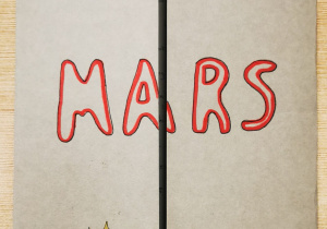 Na zdjęciu złożona do środka kartka. Na kartce napisane słowo "Mars"