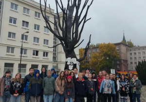 Zdjęcie grupowe uczniów stojących pod drzewem na jednej z ulic Warszawy.
