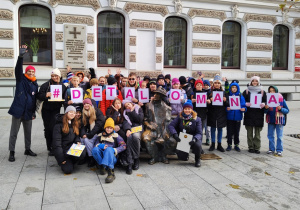 Na ulicy Piotrkowskiej stoi grupa uczniów wraz z nauczycielami. Kilka osób trzyma kartki, które układają sie w napis Detalomania.