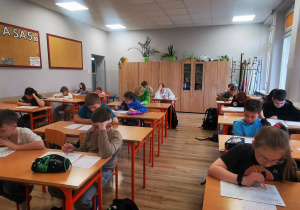 W sali lekcyjnej uczniowie siedzą w ławkach. Zdjęcie zrobione w trakcie trwania konkursu Świetlik