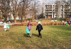 W parku Sienkiewicza na trawniku widać dzieci z workamim sprzątające śmieci.
