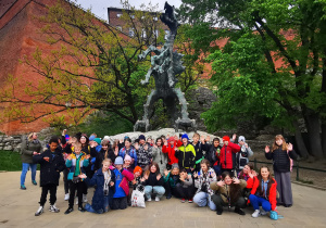 Zdjęcie grupowe uczestników wycieczki zrobione pod rzeźbą smoka wawelskiego
