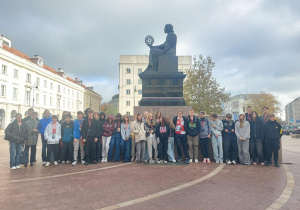 Zdjęcie grupowe uczniów stojących przed pomnikiem Mikołaja Kopernika.