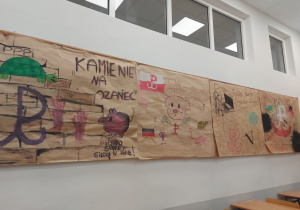 Na ścianie w klasie wiszą prace uczniów - murale wojennej Warszawy inspirowane losami bohaterów "Kamieni na szaniec"