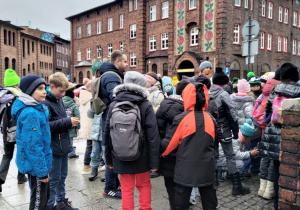 Na uliczkach osiedla górniczego Nikiszowiec stoją uczniowie biorący udział w wycieczce.